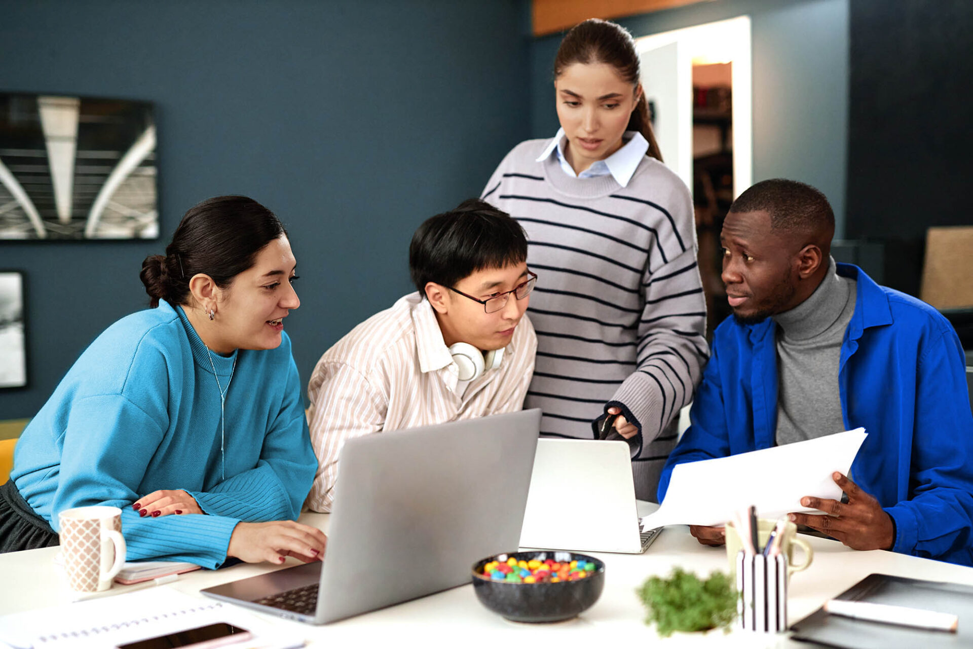 Team of professionals collaborating on AI-powered financial close tasks using laptop in office